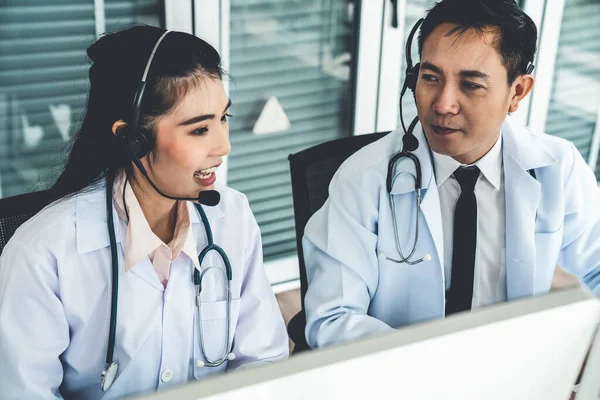 Equipe médica usando fone de ouvido conversando ativamente em videochamada na clínica do hospital — Fotografia de Stock