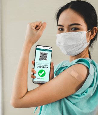 Genç Asyalı kadın cep telefonunda aşı pasaportu gösteriyor.