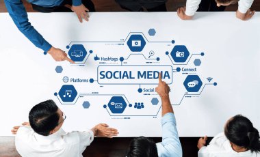 A diverse group of professionals collaborates around a table, analyzing social media strategies represented by various icons and elements of digital communication and marketing. Amity