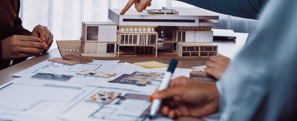 A collaborative design session featuring a scale model of a modern building, architectural blueprints, and engaged professionals brainstorming innovative ideas and solutions. SACTR