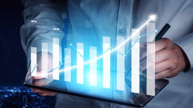A business professional studies a glowing growth chart on a tablet, set against a nighttime cityscape, depicting the future of economic progress and success. Copula