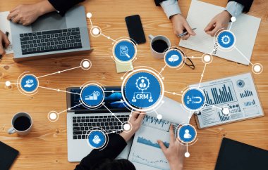 Dynamic business meeting showcasing collaboration with laptops and data visualization for effective CRM strategy development and insight sharing among team members. Amity