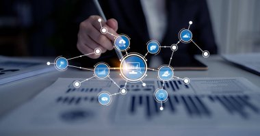 A business professional actively analyzes data trends using a digital interface filled with graphics and connection symbols in a contemporary office setting. Tessel