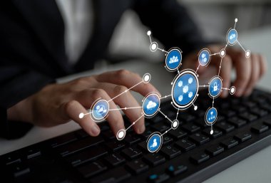 A business professional types on a keyboard, surrounded by digital icons depicting connectivity and data communication, showcasing modern technology and innovation. Tessel