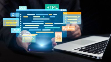 Bir kişi yanında dizüstü bilgisayar dururken çeşitli kodlama dillerini gösteren bir akıllı telefon tutar. Bu resim, dijital çalışma alanındaki modern teknoloji ve programlama yeniliğini sembolize etmektedir. Dörtgen