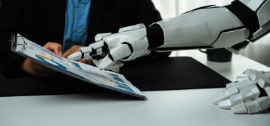 Bir robotik kol profesyonel bir ortamda bir insanla temas kurar, bir iş görüşmesi sırasında bir klasördeki görsel verileri gözden geçirir, işbirliği ve ileri teknoloji gösterir.Noogenesis