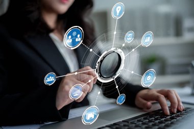 A business professional engages with a digital interface on a laptop, surrounded by innovative icons symbolizing communication, data, and technology in a modern office. Crux