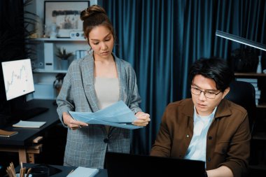 Satış müdürünün dizüstü bilgisayarında çalışan ciddi bir yüz, sekreterin gece geç saatlerde fazla mesai belgelerini verirken yönetim kurulu şirketinin veri tabanında dosya tutması için imza topluyor. İnfobahn.