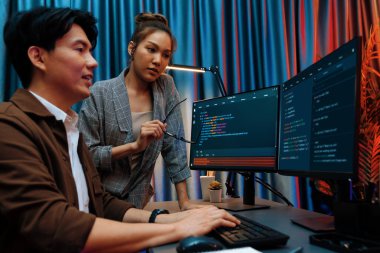 Bilgi teknolojisi geliştiricileri modern ofisteki neon ışık odasında verileri çevrimiçi olarak çalıştıran akıllı web sitesi geliştirme kodlayıcı sistemine işaret ediyorlar. İnfobahn.