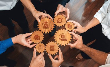 This image depicts teamwork and strategy for financial success, showcasing gears held by hands, each gear symbolizing key financial concepts like cost reduction and growth. Amity