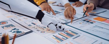 İnsan ve robot ellerin modern ofis ortamında iş haritalarını ve verileri analiz ederek yenilikleri ve takım çalışmalarını ön plana çıkaran işbirlikçi bir sahne.