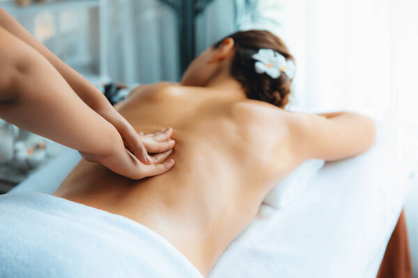 Caucasian woman customer enjoying relaxing anti-stress spa massage and pampering with beauty skin recreation leisure in day light ambient salon spa at luxury resort or hotel. Quiescent