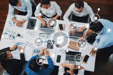 A diverse group of professionals collaborates in a modern office, focused on analyzing data and charts while utilizing technology for effective communication and strategy development. Amity