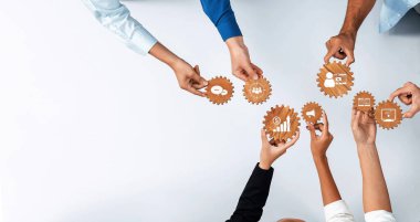 Hands hold various gear shapes symbolizing teamwork and collaboration in digital strategy, reflecting business development and innovative solutions in a modern setting. Amity