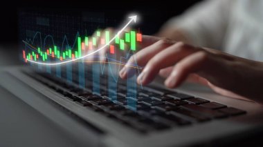 This image features hands typing on a laptop keyboard, complemented by an overlay of stock market trend graphs, symbolizing financial analysis and strategic investments. Copula