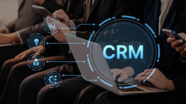 Business professionals engage with technology in a dynamic networking environment, utilizing laptops and mobile devices to enhance CRM solutions and improve client relationships. Raster