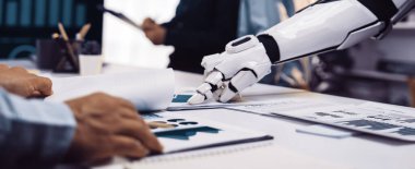 Bir robot kolu modern bir ofisteki belgelerle etkileşime geçerek, insanlar ve teknoloji arasındaki verimliliği ve yenilikçi iş akışını geliştirmek için kusursuz işbirliğini gösteriyor.