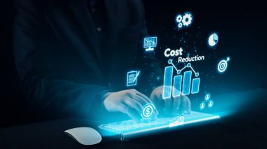 Bir işadamı, günümüz iş yerinde modern finansal analizleri temsil eden, interaktif maliyet azaltma simgeleri ve grafikleriyle çevrili, fütürist dijital bir klavyeyle ilgilenir. Dörtgen