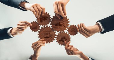 A group of hands joining together to align wooden gears, symbolizing teamwork and collaboration in business strategy, analytics, and growth in a professional environment. Amity