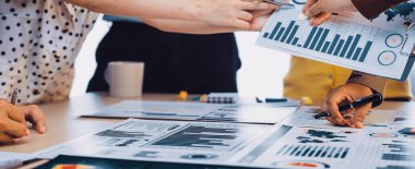 Çeşitli profesyonellerin çalışma alanı tablosu üzerinde işbirliği içinde veri şemaları ve grafikleri analiz ederek takım çalışması ve strateji sergiledikleri bir iş toplantısının dinamik bir sahnesi. SACTR