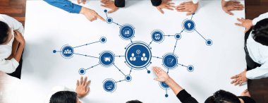 A diverse team collaborates in a modern office, engaging in a digital discussion about strategy, showcased through visual data connections on a table surface. Amity