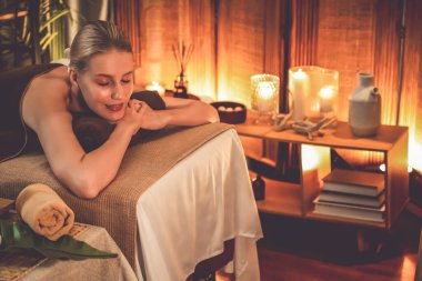 Beyaz kadın müşteri stres önleyici spa masajının keyfini çıkarıyor ve lüks otel ya da otelde sıcak mum ışığında güzellik teniyle eğleniyor. Sessiz.