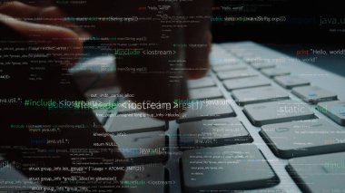 Yakın plan bir resim, bilgisayar klavyesinde teknolojinin ve dijital iletişimin entegrasyonunu sembolize eden programlama kodlarıyla yazı yazan bir el görüntüsü yakalıyor. Xenic