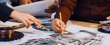 Çeşitli mühendislerden oluşan bir ekip, tasarım ve fikirlerini geliştirmek için kalem ve defter gibi araçlar kullanarak ayrıntılı planlar ve mekanik çizimler üzerinde işbirliği yapıyor. SACTR