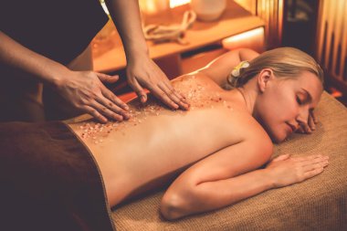 Lüks spa salonlarında sıcak mum ışığında cilt bakımı yaptıran kadın müşteri. Sağlık Spa vücut fırçasında tuz temizleme güzellik tedavisi. Sessiz.