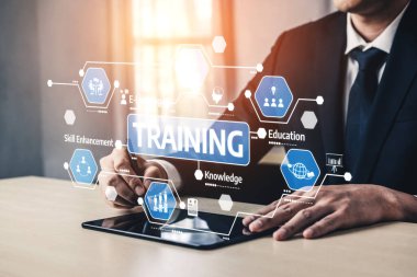 Bir işadamı, profesyonel bir ofiste modern eğitim kavramlarını gösteren dijital bir tabletle etkileşime girer. Kariyer gelişimi için beceri, bilgi ve yenilik vurgulanıyor. Tessel