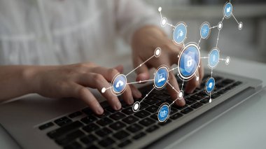 Bu resim, modern teknoloji temalarını temsil eden dijital bir manzaradaki güvenlik ve bağlantıyı sembolize eden ikonlarla çevrili bir dizüstü bilgisayarda yazı yazan elleri yakalar. Tessel