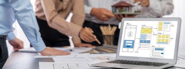 İç mimar tasarımcı grubu, daha kesin tasarım için planlar ve dizüstü bilgisayar ekran mimari yazılımı üzerinde birlikte tartışıyorlar. Modern ev tasarımı ve yenileme. İçgörü