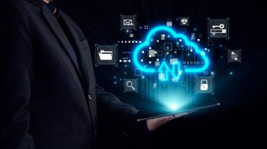 Takım elbiseli bir işadamı, ileri bağlantı ve dijital yeniliği temsil eden ikonları yükleme ve indirme ile aydınlık bir bulut arayüzü içeren bir tablet tutuyor. Dörtgen