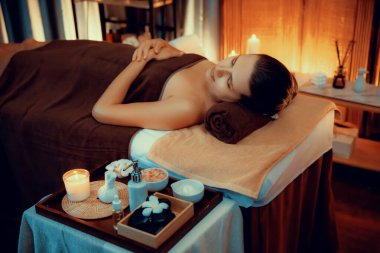 Beyaz kadın müşteri stres önleyici spa masajının keyfini çıkarıyor ve lüks otel ya da otelde sıcak mum ışığında güzellik teniyle eğleniyor. Sessiz.
