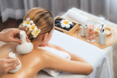 Sıcak bitkisel top spa masaj vücut tedavisi, masör kadın vücuduna nazikçe şifalı bitki torbası bastırıyor. Aromaterapi dinlenme sükuneti ve sükuneti kaplıca salonundaki atmosferi aydınlatıyor. Sessiz.