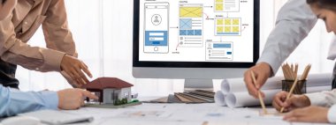 İç mimar tasarımcı grubu, daha kesin tasarım için planlar ve dizüstü bilgisayar ekran mimari yazılımı üzerinde birlikte tartışıyorlar. Modern ev tasarımı ve yenileme. İçgörü