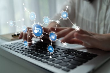 Teknoloji, iletişim, veri analizi ve modern arayüzleri temsil eden soyut dijital sembollerle çevrili bir dizüstü bilgisayarda yazı yazan ellerin yakın çekimi. Tessel