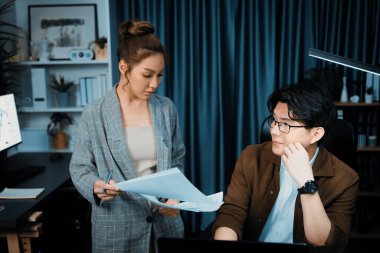 Satış müdürünün dizüstü bilgisayarında çalışan ciddi bir yüz, sekreterin gece geç saatlerde fazla mesai belgelerini verirken yönetim kurulu şirketinin veri tabanında dosya tutması için imza topluyor. İnfobahn.