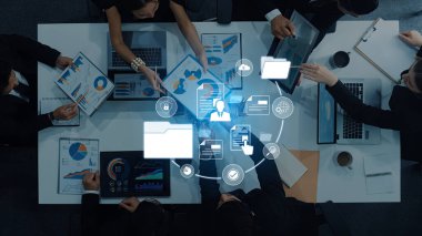 Çeşitli profesyonel gruplar, modern ofis ortamında ekranlarda gösterilen dijital veri ve grafikleri analiz ederek ortak bir toplantıya katıldı. Çapraz