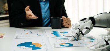 Bir insan ve bir robot, teknoloji ve insan görüşü arasındaki modern işbirliğini gösteren grafikleri ve veri analizlerini tartışmak için bir iş toplantısına katılırlar.