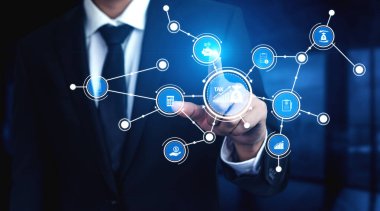 Takım elbiseli bir işadamı, gelecekteki simgeleri gösteren dijital bir arayüzle etkileşime giriyor. Bu resim kurumsal bir ortamda yenilik, finans ve veri bağlantısını sembolize eder. Tessel