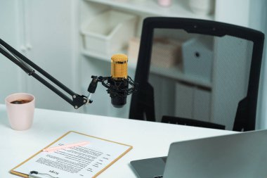 Beyaz masada duran tüm canlı yayın setleri dizüstü bilgisayar, mikrofon, kulaklık, ağaç, senaryo notu ve kalemden oluşur. Sosyal medyada canlı yayında sunucu kanalı için beklemedeyiz. Taktik.