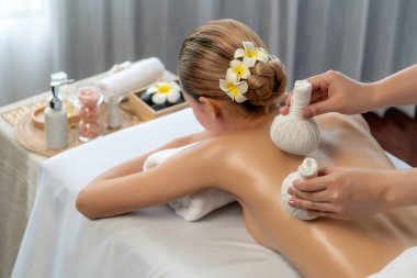 Sıcak bitkisel top spa masaj vücut tedavisi, masör kadın vücuduna nazikçe şifalı bitki torbası bastırıyor. Aromaterapi dinlenme sükuneti ve sükuneti kaplıca salonundaki atmosferi aydınlatıyor. Sessiz.