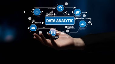Bu resim, veri analizi kavramlarının dijital temsilini tutan ve teknolojiyi ve veri görselleştirmesini sembolize eden çeşitli unsurları gösteren bir eli gösteriyor. Tessel