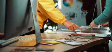 Modern bir ofis masasında teknoloji ve proje materyalleri ile fikirleri tartışan ve paylaşan, yaratıcılık ve takım çalışmasını vurgulayan işbirlikçi bir çalışma alanı tasarımcısı. SACTR