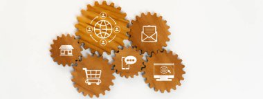 Bu resim, dijital iletişimi ve e-ticareti temsil eden, bağlantı ve modern iş kavramlarını gösteren ikonlarıyla ahşap dişlilerin bir düzenlemesini içerir. Dostluk