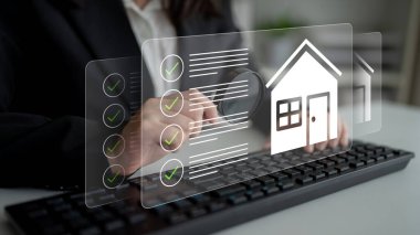 Modern ofis ortamında gayrimenkul yönetimi kavramlarını vurgulayan bir profesyonel klavye ile dijital bir kontrol listesi ve bir ev ikonu yönetirken etkileşim halindedir. Gantry
