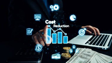 Bir işadamı, çeşitli finansal kavramları temsil eden para ve dijital simgelerle birlikte bir dizüstü bilgisayardaki veri trendlerini kullanarak maliyet azaltma stratejilerini analiz eder. Dörtgen