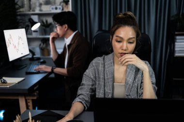 Modern ofiste gece geç saatlerde arka tarafta çalışan iş arkadaşı ile birlikte veri analizi sosyal medya çevrimiçi proje işini rapor etmek için bilgisayara odaklanan iş kadınının ciddi yüzü. İnfobahn.