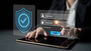 Profesyonel bir kadın, modern teknoloji ve dijital güvenlik uygulamalarını çağdaş bir çalışma alanında vurgulayarak, güvenli giriş için bir tablet cihazıyla etkileşime girer. Gantry